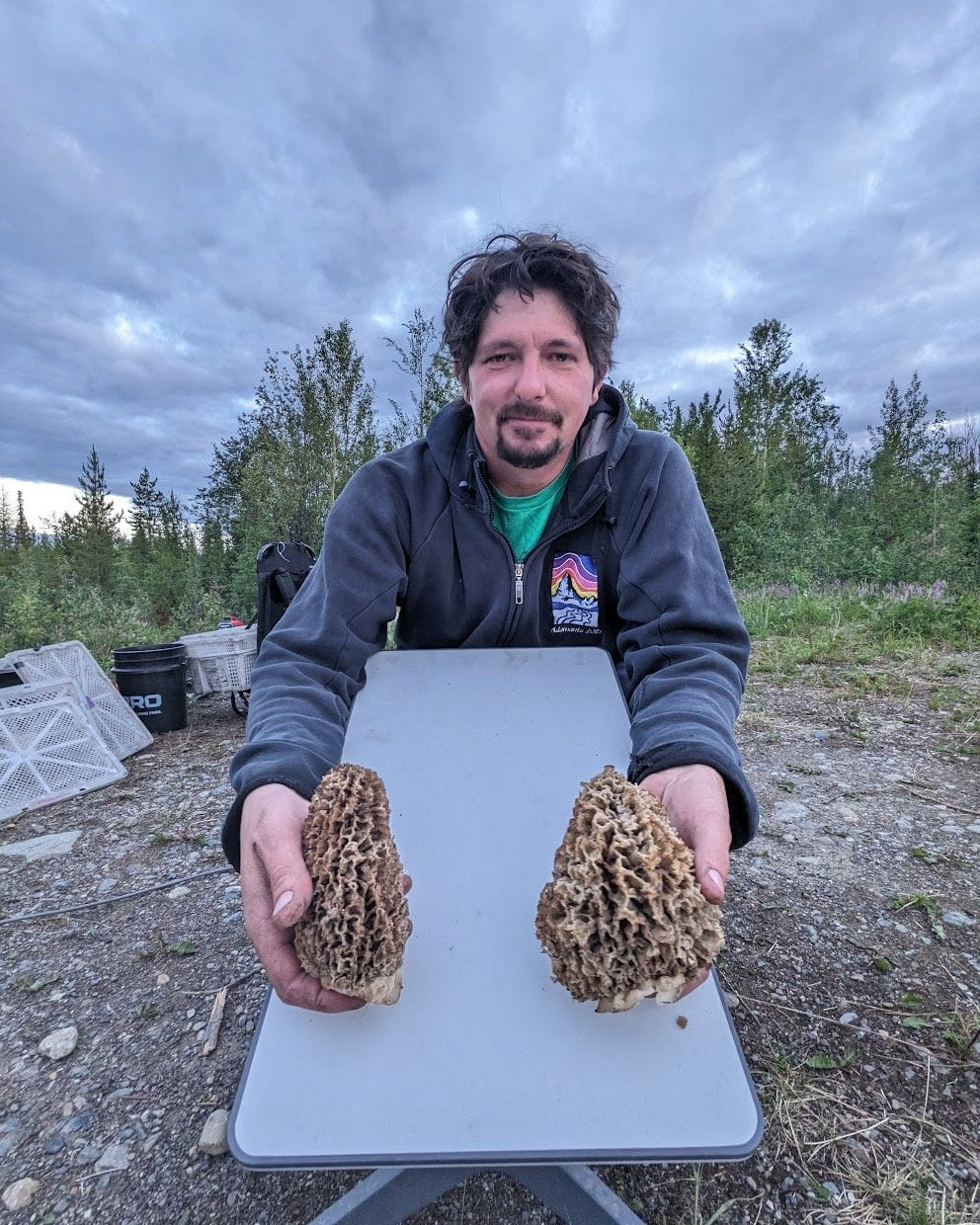 Jesse holding two large mushrooms outdoors